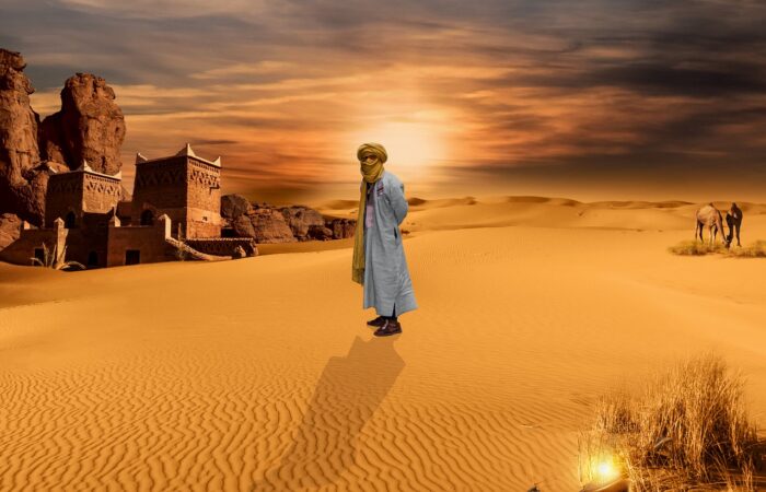 Man walking across golden sand dunes in the Sahara Desert at sunset, Morocco