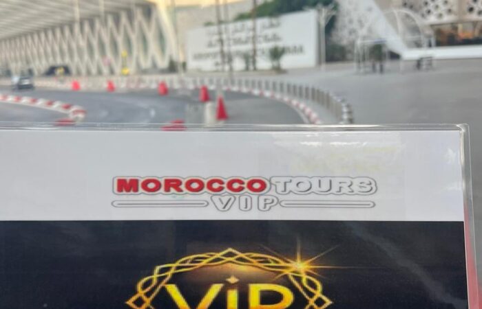 Morocco Tours VIP welcome sign held in front of Marrakech Menara Airport’s modern terminal