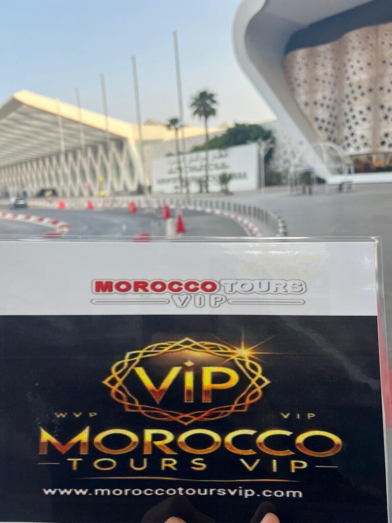 Morocco Tours VIP welcome sign held in front of Marrakech Menara Airport’s modern terminal