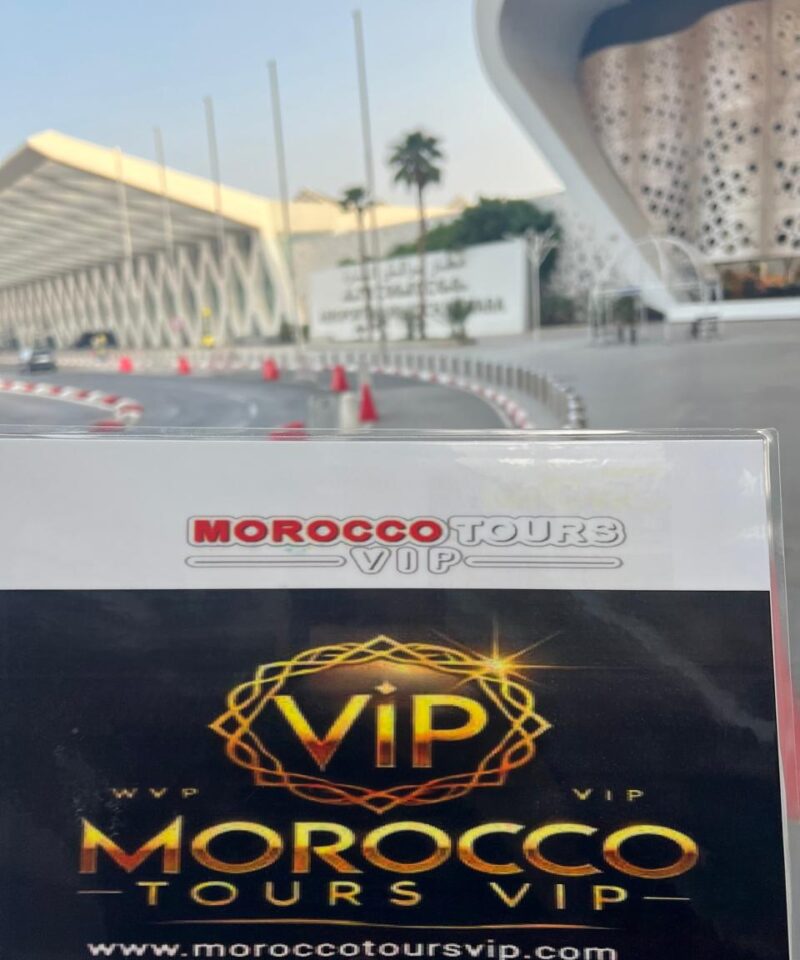 Morocco Tours VIP welcome sign held in front of Marrakech Menara Airport’s modern terminal
