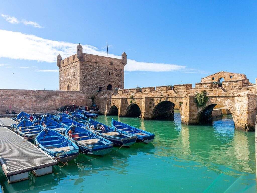 View of blue fishing boats docked by the Skala fortress in Essaouira, Morocco