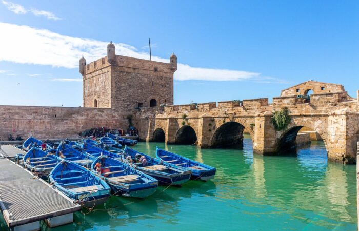 View of blue fishing boats docked by the Skala fortress in Essaouira, Morocco