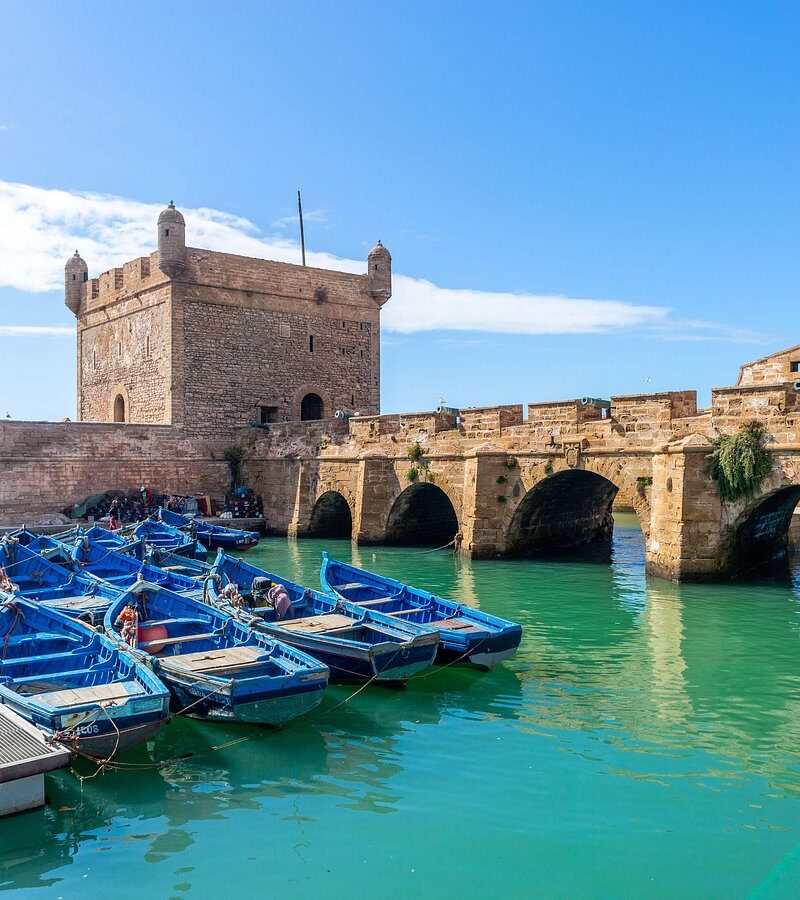 View of blue fishing boats docked by the Skala fortress in Essaouira, Morocco