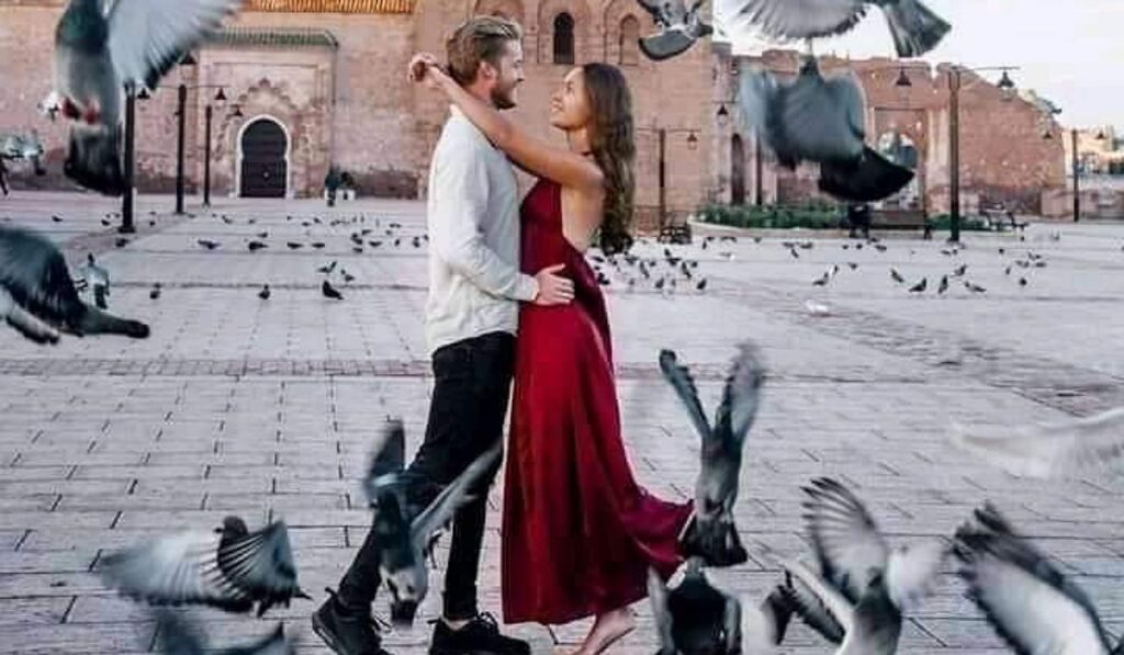 Couple on honeymoon in Marrakech feeding pigeons near historic city walls