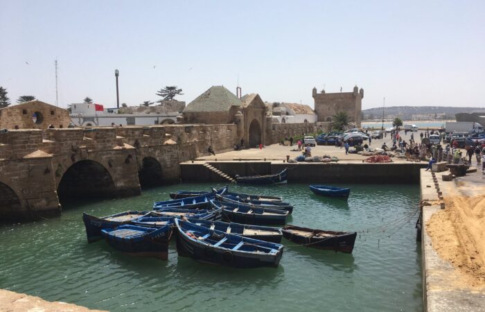 Essaouira port with traditional blue fishing boats and historic city walls in the background, Morocco.
