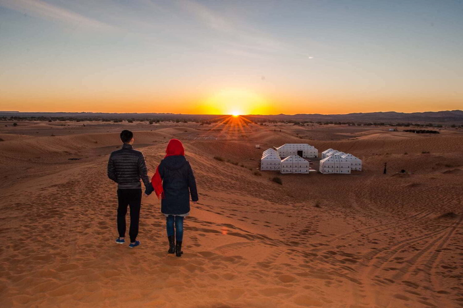 Couple walking at sunset in Erg Chebbi Sahara dunes during Marrakech to Merzouga 3-Day Desert Tour