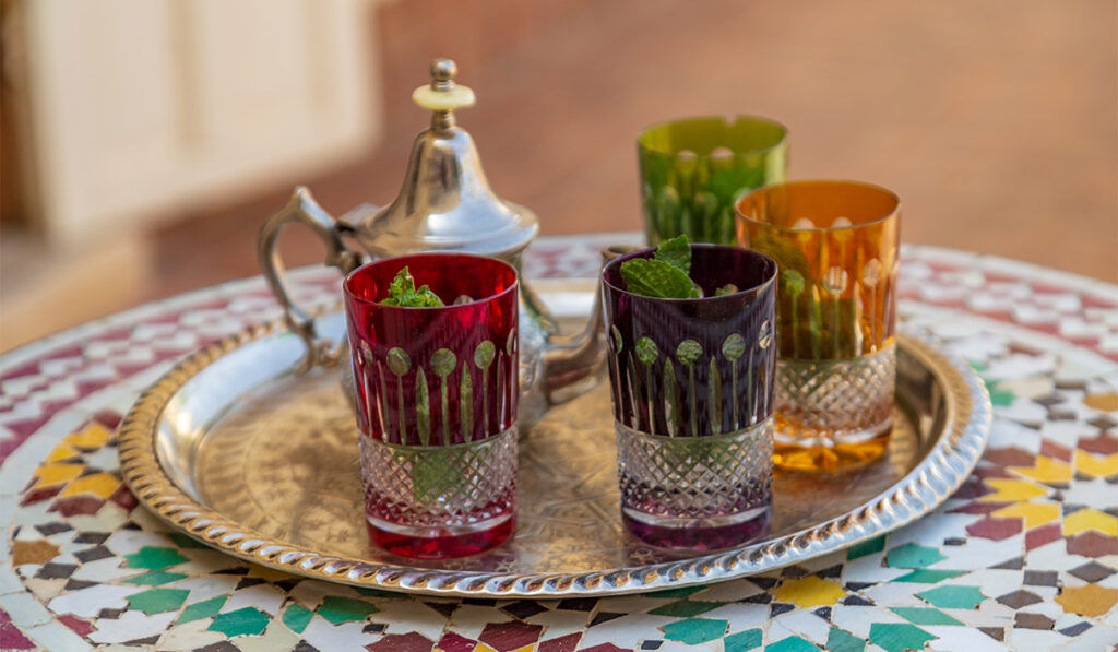 Traditional Moroccan tea served in colorful glasses on a silver tray with fresh mint