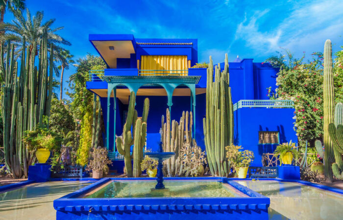 Bright blue and yellow pavilion in Majorelle Garden surrounded by lush plants in Marrakech