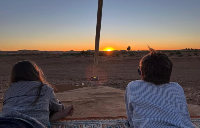 Private Morocco tour travelers watching the sunset in the Sahara Desert near Merzouga